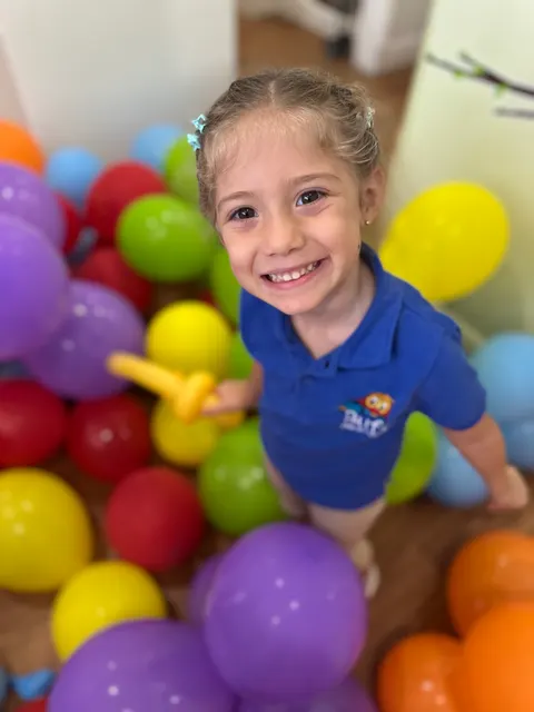 A girl laughing in a pit of colorful balls