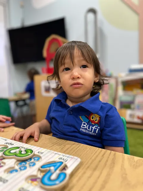 A toddler boy sitting at a table with an alphabet puzzle