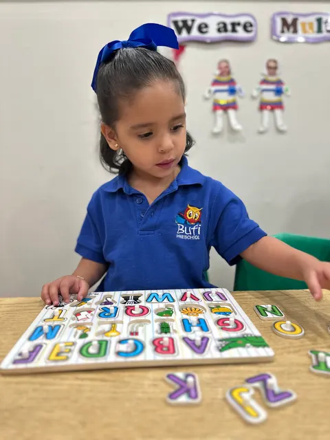 A girl reaching for letters on an alphabet puzzle board