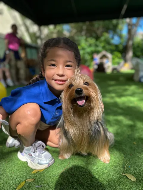 A girl crouching next to a small dog outdoors