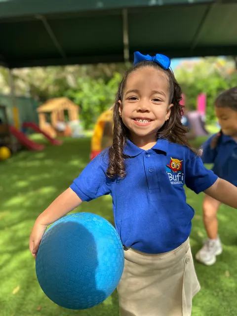 A girl holding a blue ball on the playground