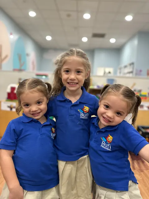 Three girls with their arms around each other in the classroom