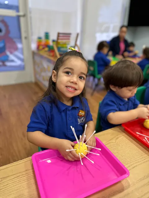 A girl working on a toothpick craft at the table