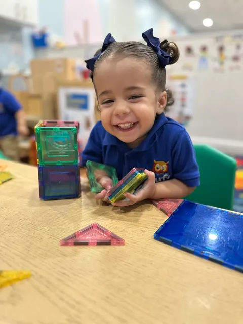 A girl smiling while playing with magnetic tiles