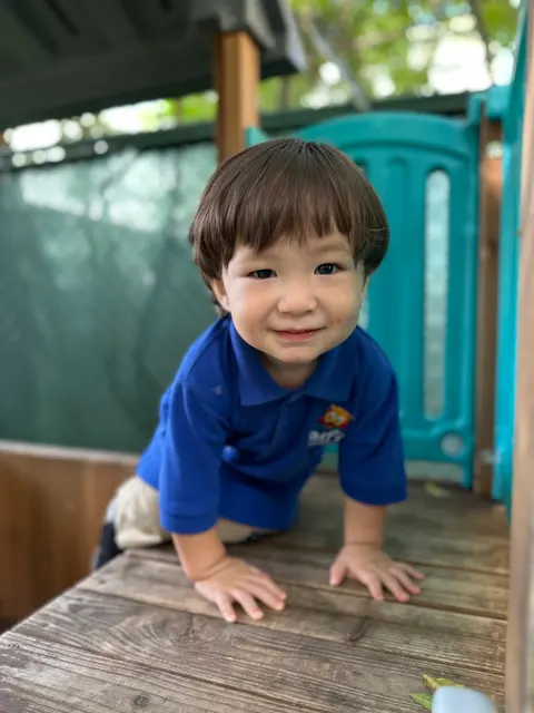A toddler boy climbing on the outdoor play structure