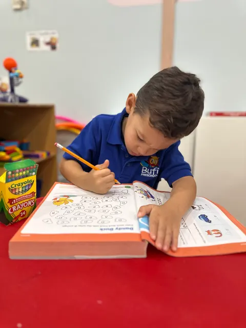 A boy tracing letters in his workbook