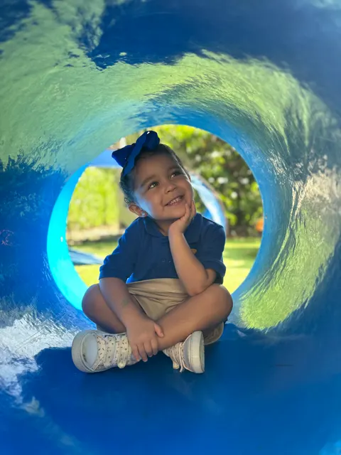 A girl resting her chin on her hand inside a play tunnel