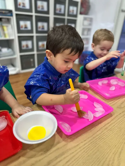 Un niño con polo azul de Bufi pintando con un pincel amarillo