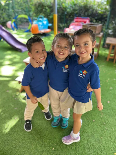 Tres niños sonriendo juntos en el jardín