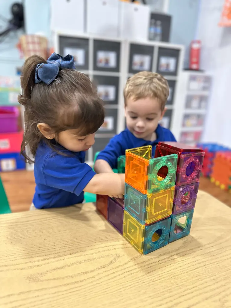 Dos toddlers construyendo con bloques magnéticos de colores