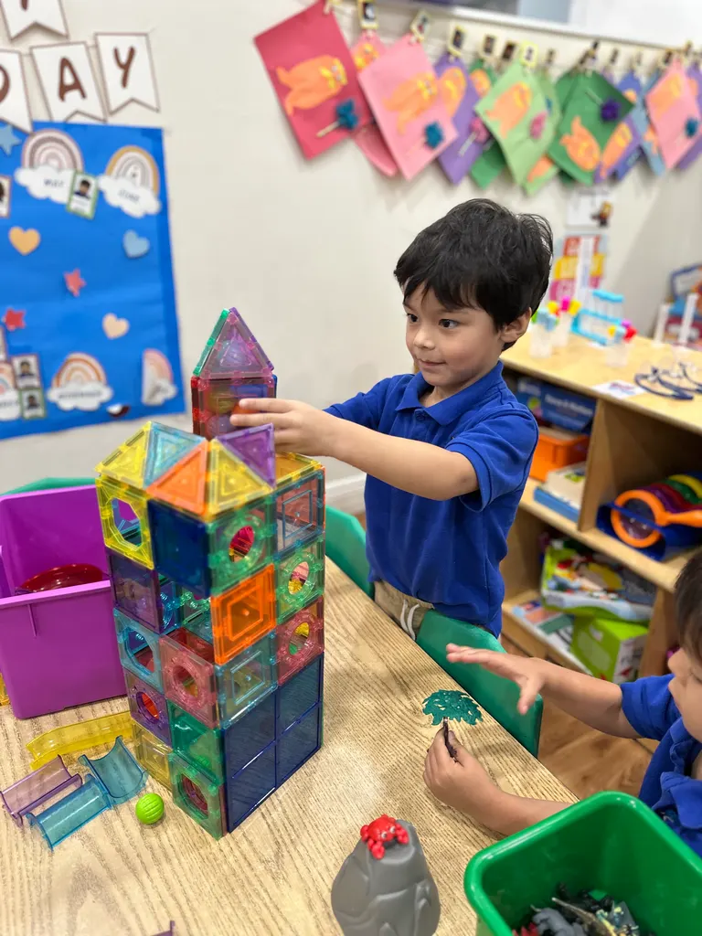Un niño apilando una torre alta de bloques magnéticos en el salón